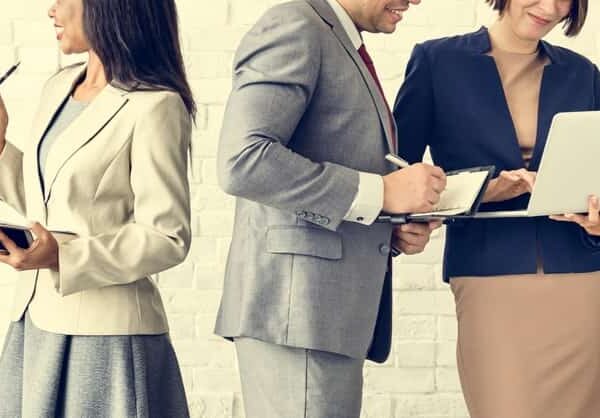 business people standing while looking at laptops